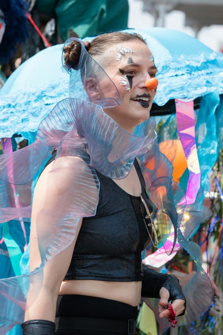 A vibrant festival portrait featuring a woman with a uniquely painted face and creative costume.