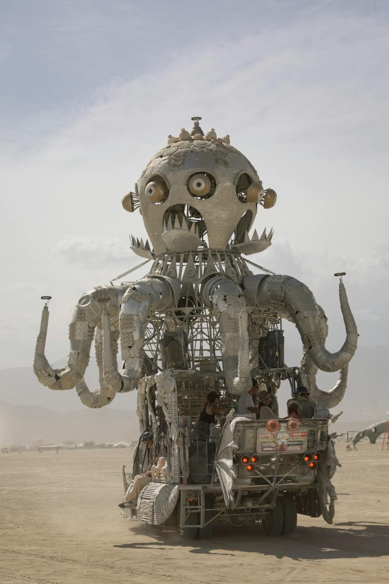 Intricate metal octopus art car moving across desert at Burning Man festival.